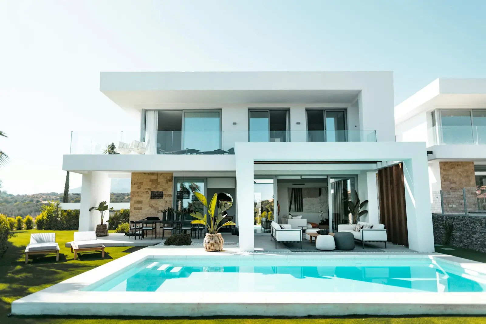 Piscine bordant une villa blanche contemporaine sous un ciel dégagé